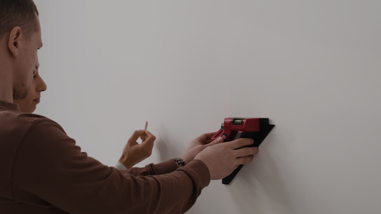 Man Using Laser Level to Mark Wall for Installation