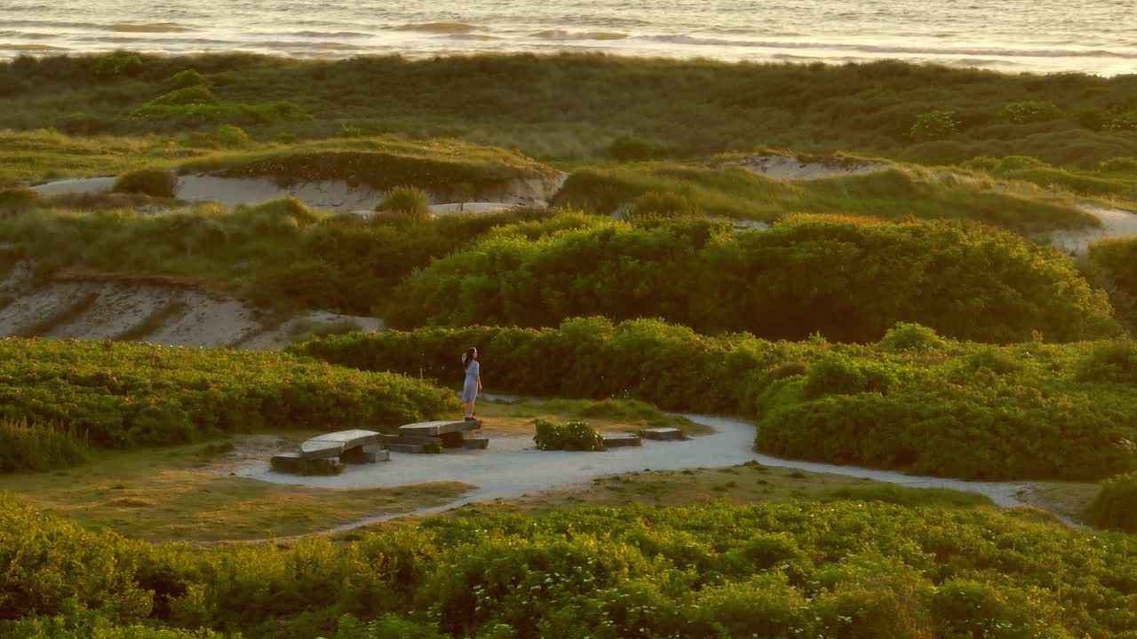 dunas costeras al atardecer con una mujer