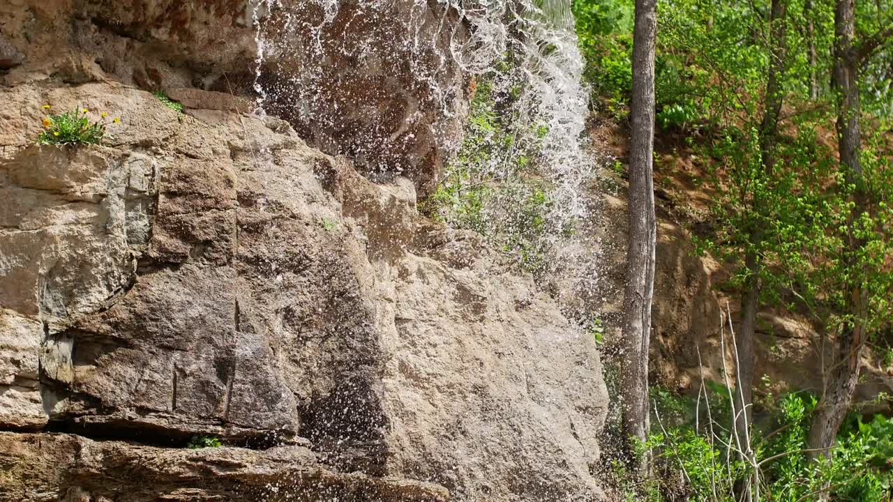 hermosa cascada desde un acantilado en el bosque. 4k video de agua que fluye, arroyo que fluye entre las piedras. arroyo en el bosque