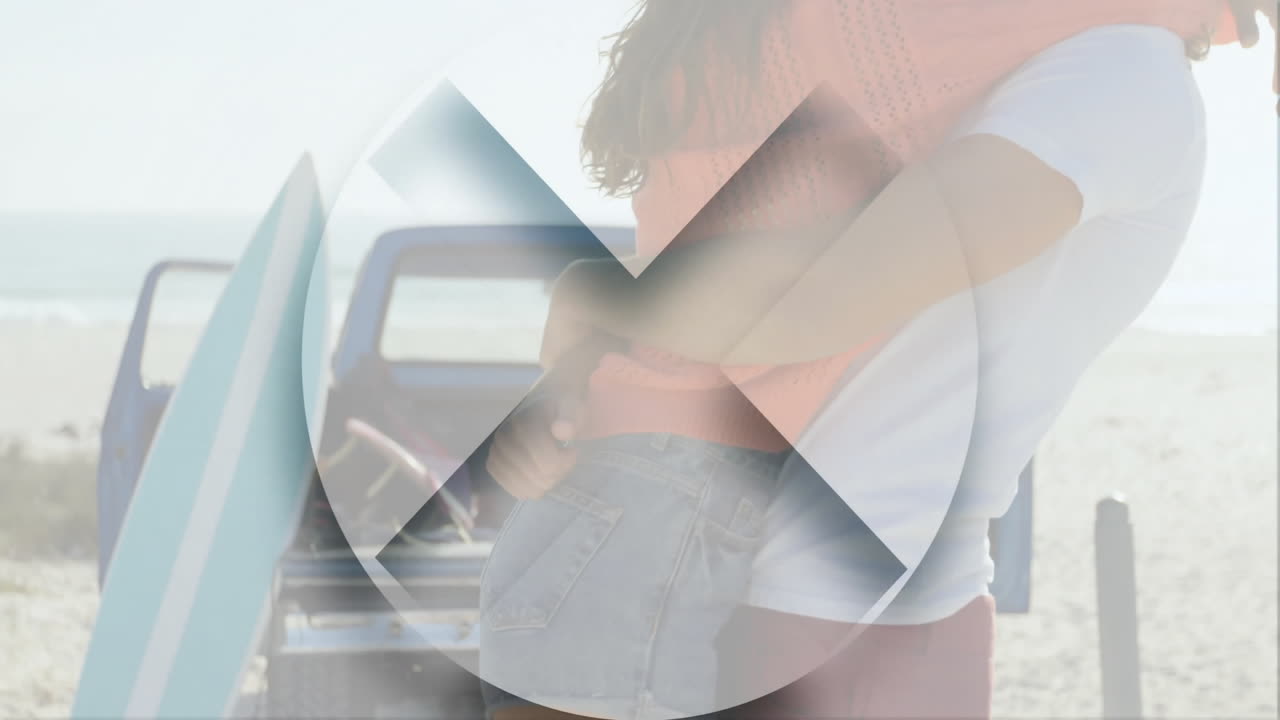 By beach, couple embracing with surfboard and truck in background