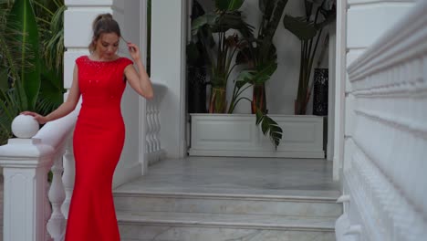 Hermosa-Mujer-Rubia-Con-Vestido-Rojo-Posando-En-Las-Escaleras-Blancas-De-La-Mansión