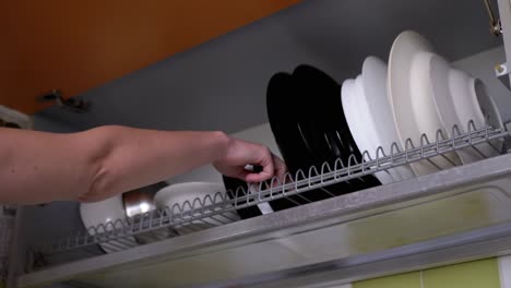 woman opens door of the cupboard with dish drainer and puts washed plate. 4k