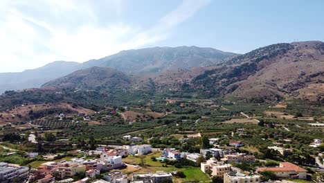 mountain range and small town in crete, aerial ascend view