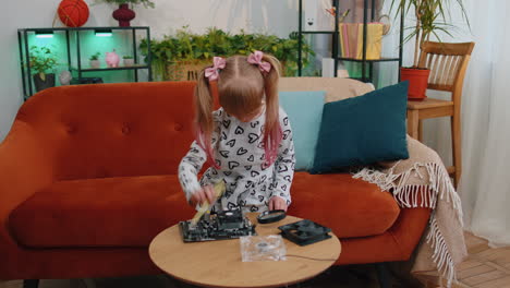 niña pequeña reparando la placa principal de la computadora parte de la tecnología, usando lupa en casa