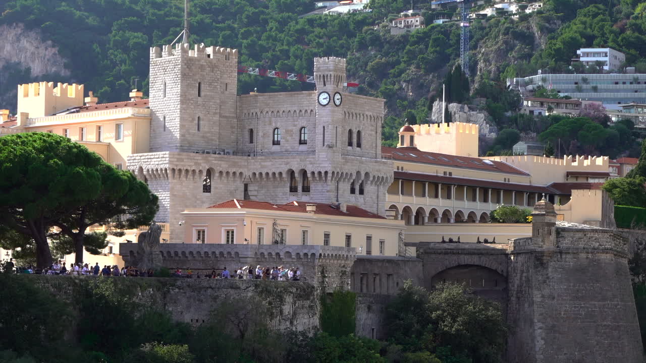 Distant view of the Prince's Palace of Monaco and medieval ramparts perched above Monaco, with visitors walking around