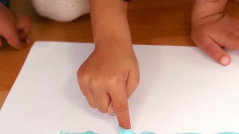 los niños pintan con los dedos en hojas de papel