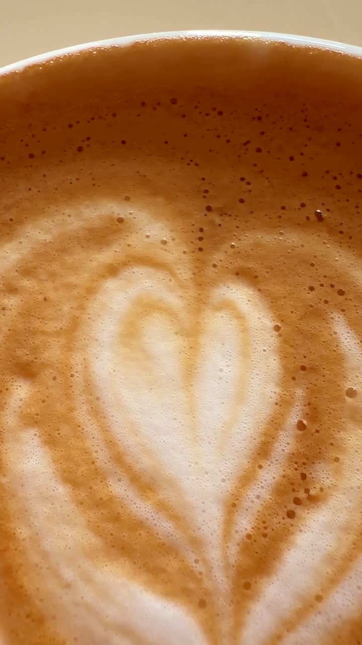 Latte art a forma di cuore che si dissolve lentamente nella schiuma di caffè
