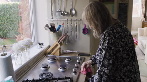 woman cleaning a cooktop in a kitchen