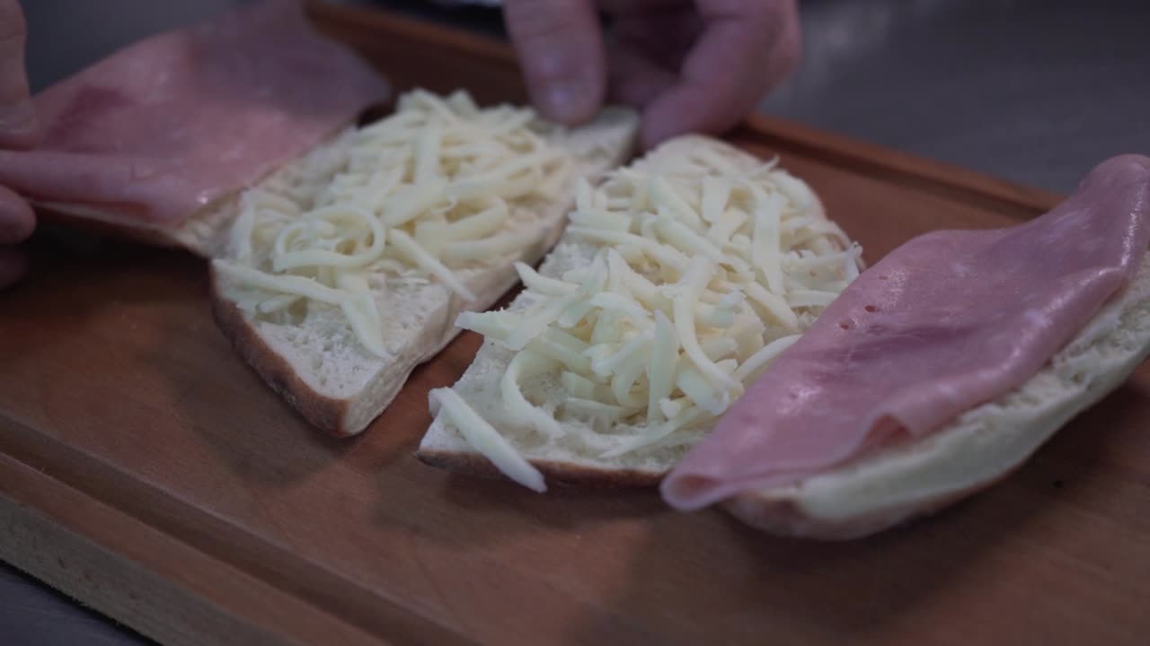 나무 판자에서 햄과 치즈를 곁들인 샌드위치를 열었습니다.