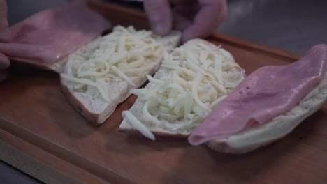 sándwiches abiertos con jamón y queso tomados de una tabla de madera