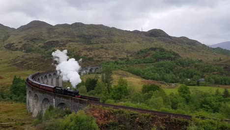 viaducto ferroviario de glenfinnan en escocia con el tren de vapor jacobita en verano con clima lluvioso