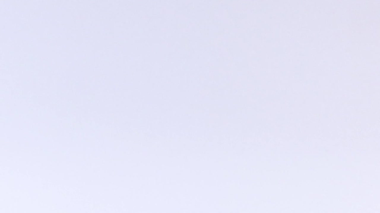 A golf ball is captured in mid-air against a plain white background.