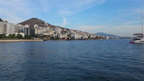 Yacht-Vor-Anker-In-Der-Bucht-Von-Saranda:-Erkunden-Sie-Die-Touristenstadt-Mit-Strandpromenade-Und-Hotels,-Ihr-Perfektes-Sommerurlaubsziel