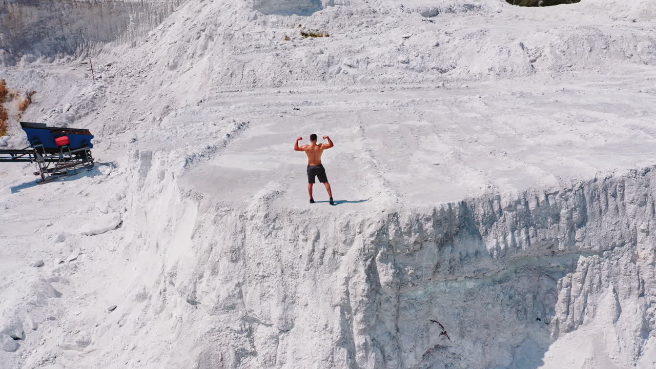 Model man with naked torso. Aerial view of attractive young shirtless athletic muscle man standing on mountain
