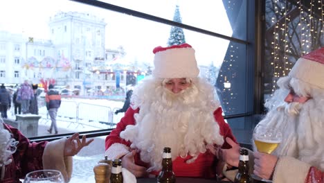 drunk santa claus sleeps in a cafe at the table drunk santa claus sleeps in a cafe at the table a man with a fake white beard in a suit of santa claus he has alcoholism depression negativism bad santa a group of three santa clauses