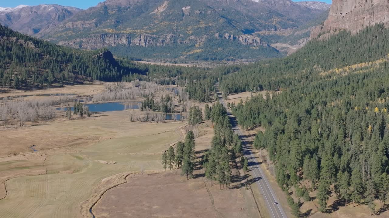Scenic aerial view of Colorado highway in fall amid forest and mountains