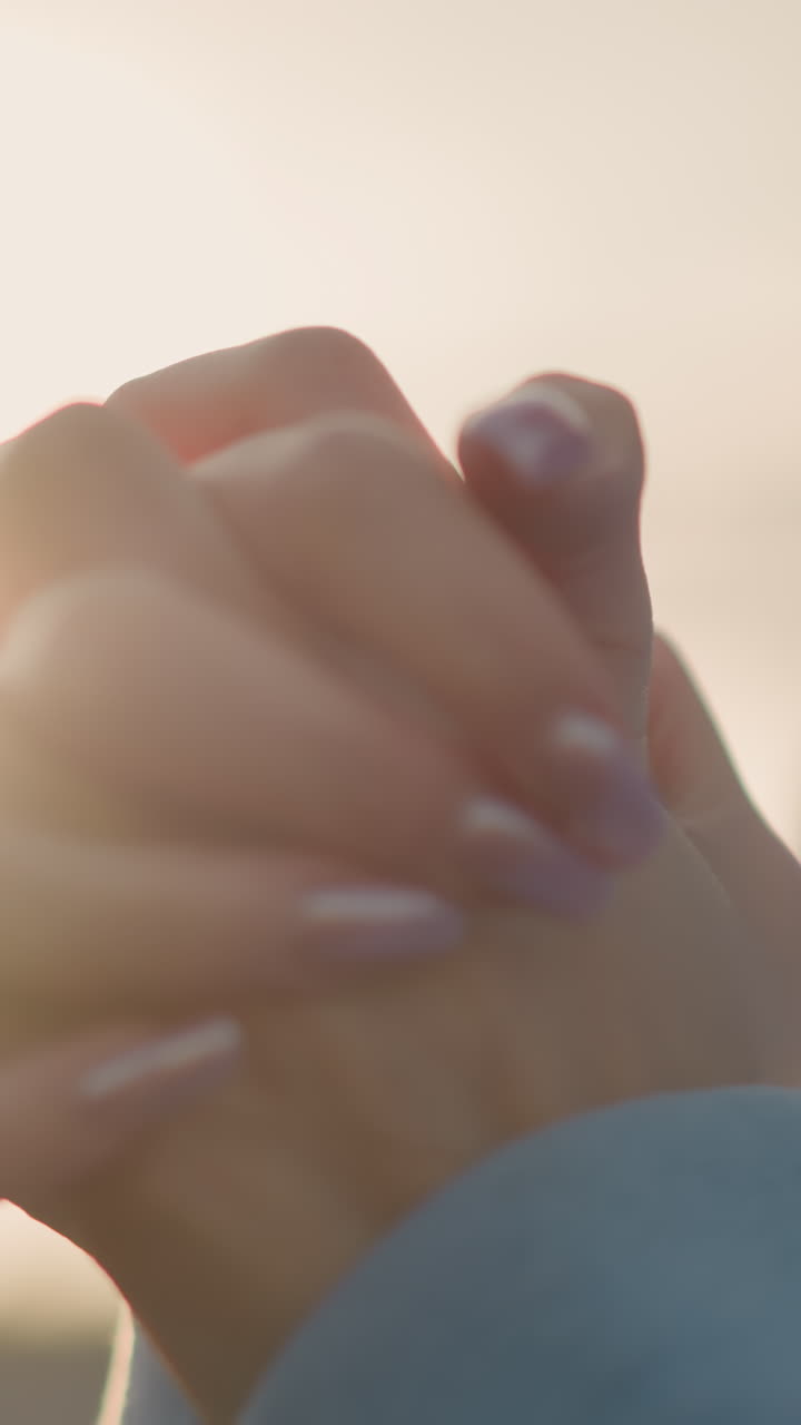 화려한 손을 가진 여성이 파란 스웨터를 입고 손목을 회전하는 클로즈업, 은 빛이 손을 둘러싸고 빛나고, 야외 피트니스 루틴에서 우아한 손목 움직임을 강조합니다.