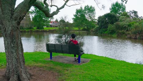 lonely man setting on the stool looks towards the lake