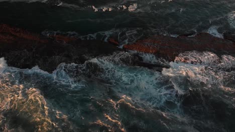 aerial drone footage capturing ocean waves crashing against a rocky coastline