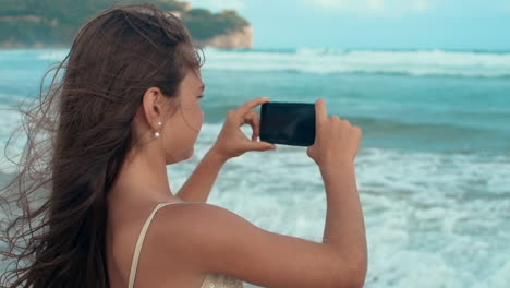 niña alegre disfrutando del paisaje en la orilla del mar. adolescente usando el teléfono celular en la playa.