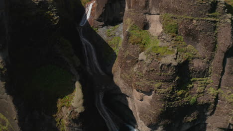 Birds-eye-view-of-waterfall-in-Fjadrargljufur-canyon-in-south-Iceland.-Beauty-on-earth.-Aerial-view-of-cascade-in-deep-gorge-in-icelandic-highlands-jumping-into-Fjadra-river.-Iceland-landscape