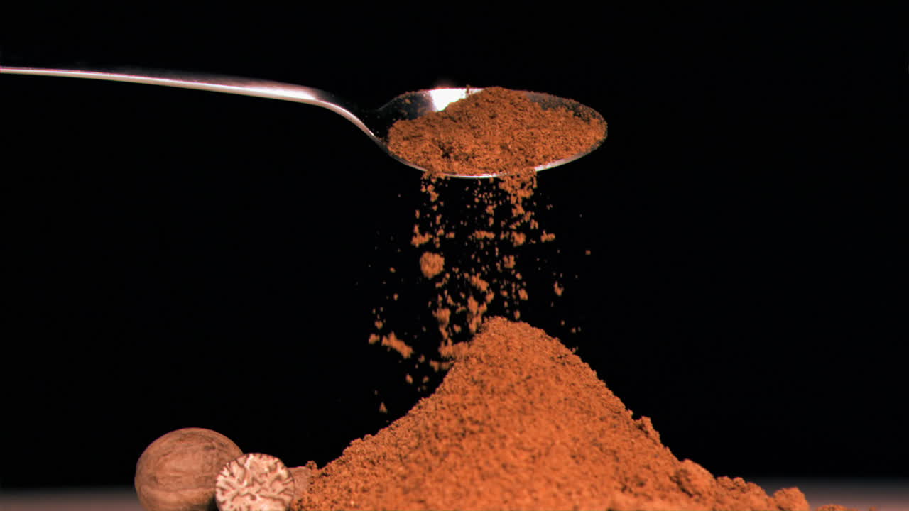 Spoon pouring powder in super slow motion on piled up powder