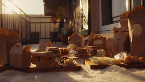 a variety of takeout food items laid out on a balcony during golden hour