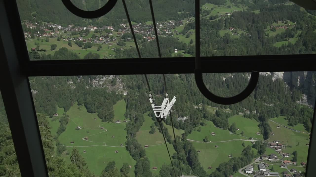 A lush green mountain view out of the window of a decending cable car in Switzerland