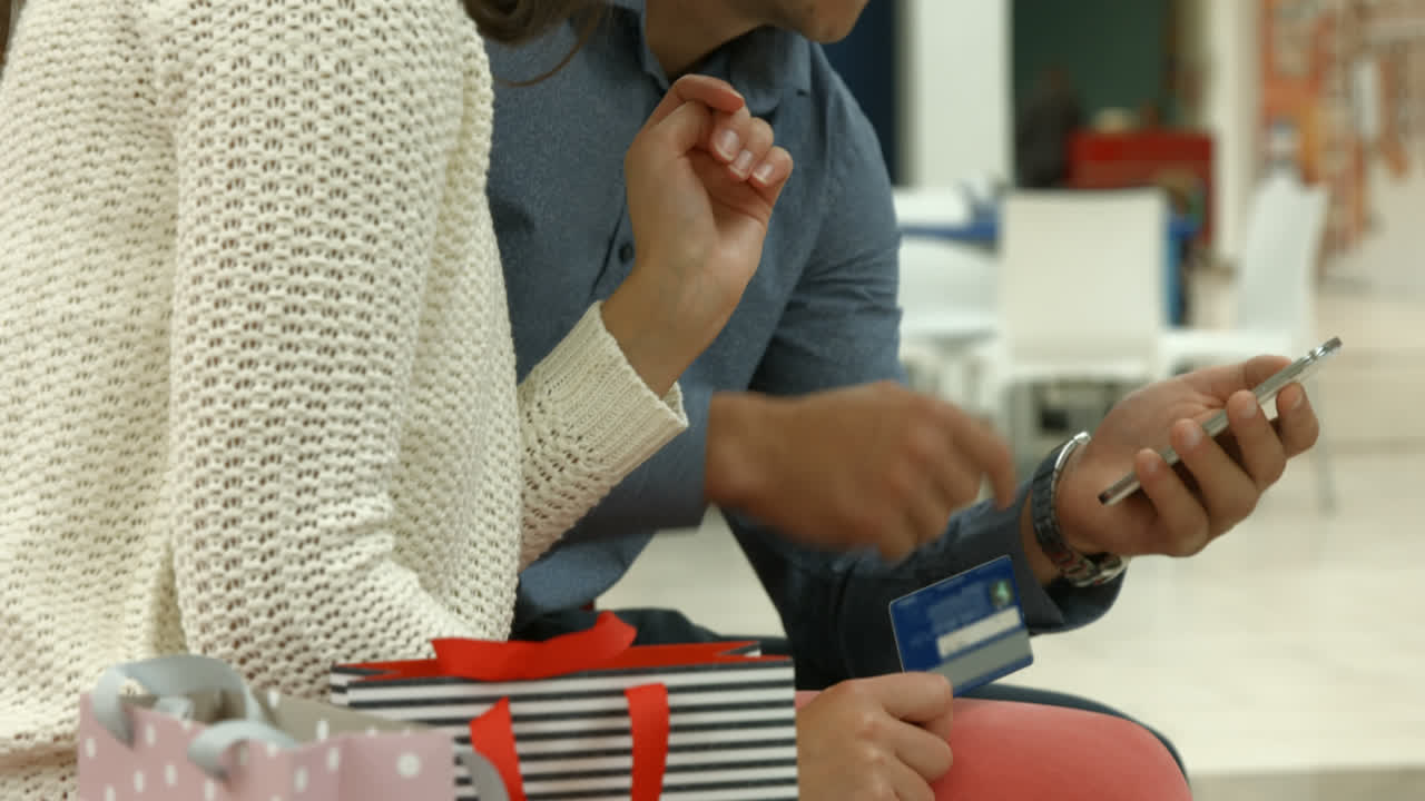 Couple with smartphone and credit card discussing 