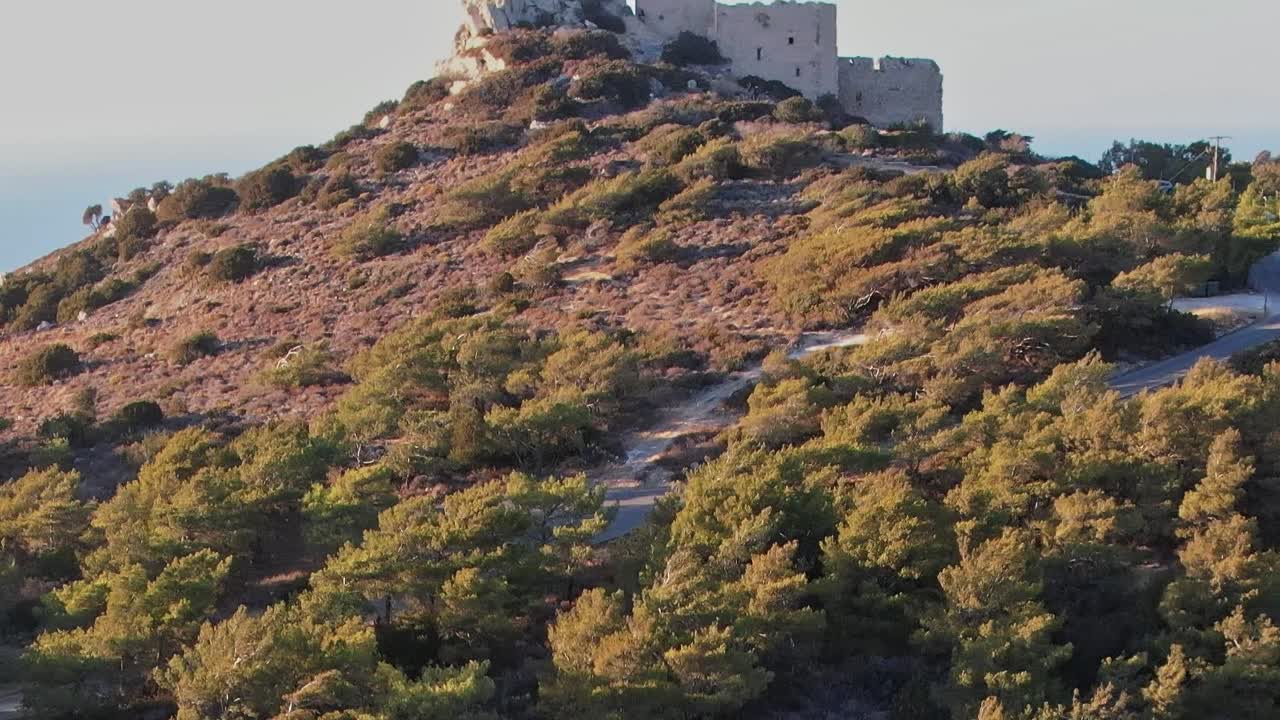 Sentieri e alberi a Rodi, in Grecia, alla luce della sera vicino a una collina