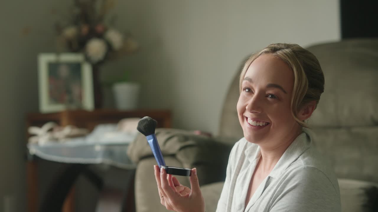 disparo en cámara lenta de una mujer joven en pijama aplicando maquillaje por la ventana riendo