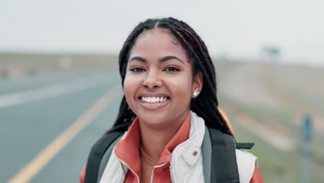 portrait of a smiling woman with braids and backpack on a road