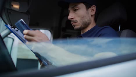 vídeo en primer plano del mensajero usando la tableta mientras está sentado en el coche