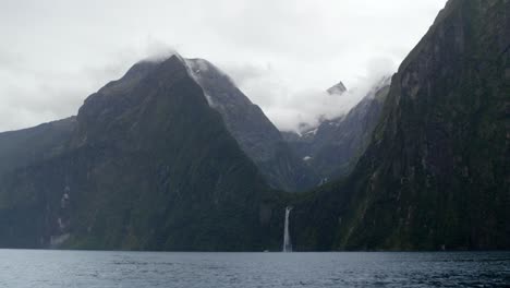 Waterfall-running-off-Mountains-above-a-beautiful-lake-on-a-cloudy-day