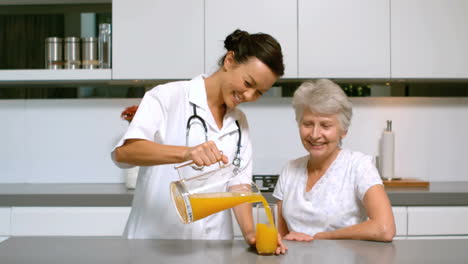 Home-nurse-pouring-juice-for-patient-in-kitchen