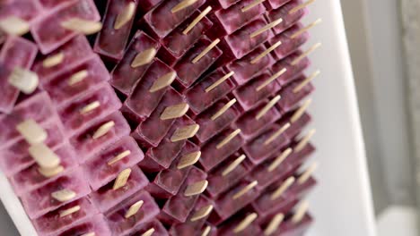 tray full of freshly prepared grape and red fruit popsicle in an ice cream factory