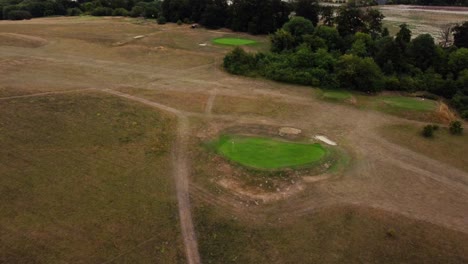 aerial high shot over a golf course hole on a green, camera tilting in royston, hertfordshire, england, uk