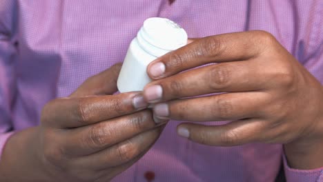 persona que sostiene un frasco de medicamento blanco