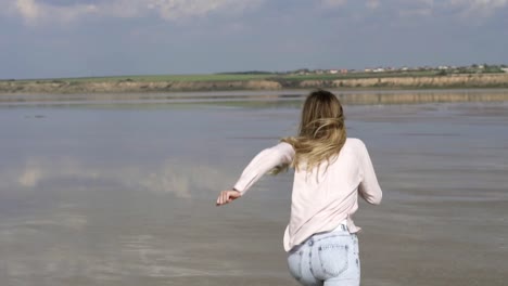 Carefree-woman-in-casual-is-running-on-shallow-of-lake-at-summer