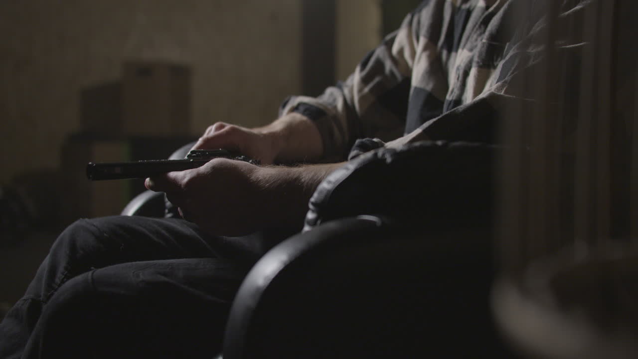 어두운 창고 내부에서 총을 들고 있는 남자 손, 클로즈업  ⁇