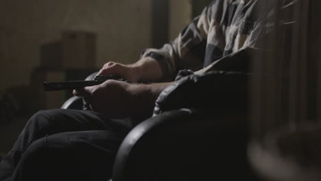 Male-hands-holding-gun-in-dark-warehouse-interior,-close-up-shot