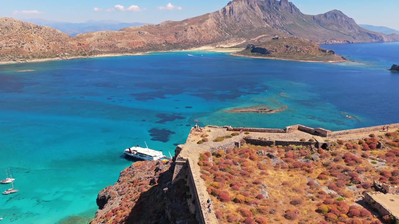 Gramvousa, Yunanistan'daki Gramvousa yarımadası dağının altında yer alan Venedik kale adası ve turkuaz lagünün havadan drone görüntüsü.