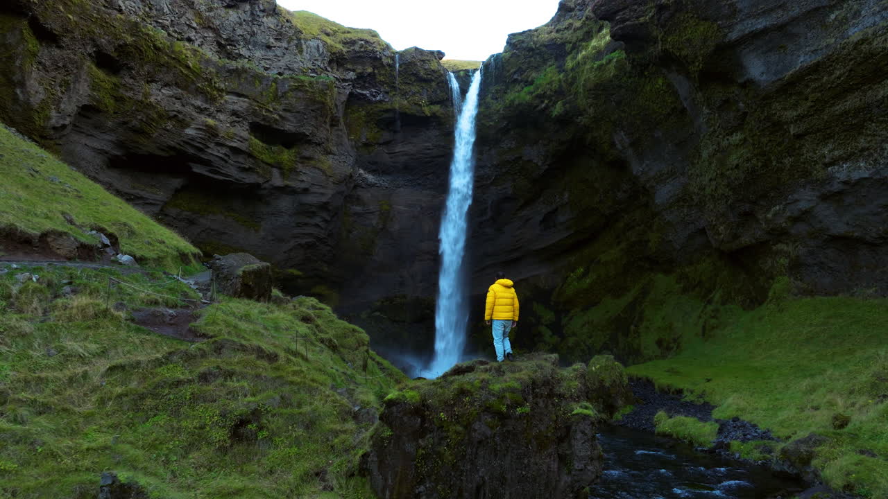 hombre de pie en la roca para admirar la belleza de la cascada de kvernufoss en islandia