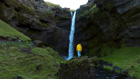 Man-Standing-On-The-Rock-To-Admire-The-Beauty-Of-Kvernufoss-Waterfall-In-Iceland