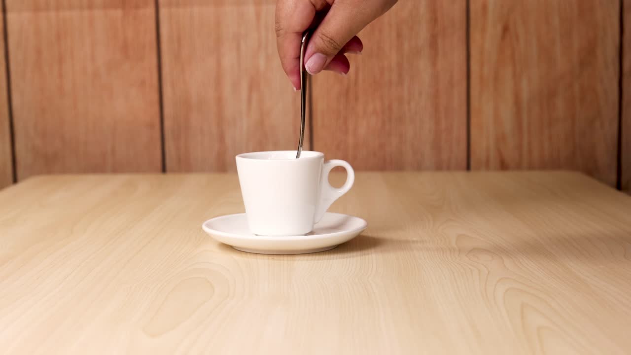 Hand stirring coffee with a spoon