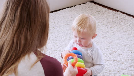 Mutter-Mit-Kleinkind-Sitzt-Auf-Dem-Boden-Und-Spielt-Mit-Plastikringen