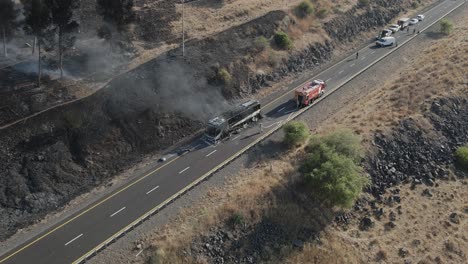 Firefighters-spraying-burning-bus-with-water-hose-from-fire-truck,-drone-view