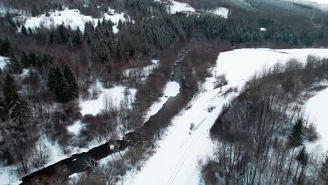 Astonishing-aerial-view-white-snowy-landscape-with-river-stream,-circle-pan