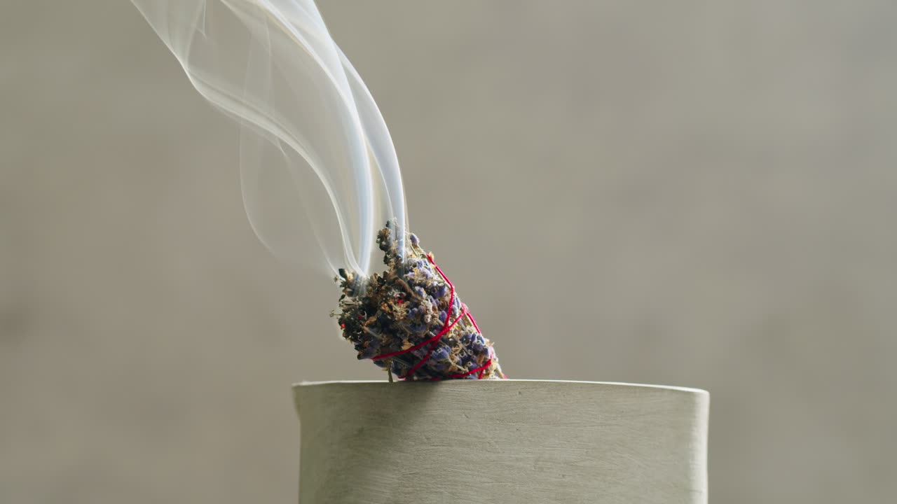 Person holding Palo Santo wood stick in hand, aromatic Palo Santo burning on black background, smoke spreading around, slow motion video clip, high quality 4k close up footage. High quality 4k footage