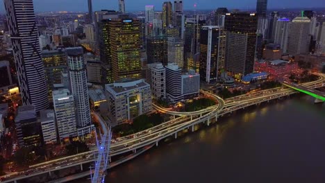 dolly aerial view of a modern city center with highway along riverside at night